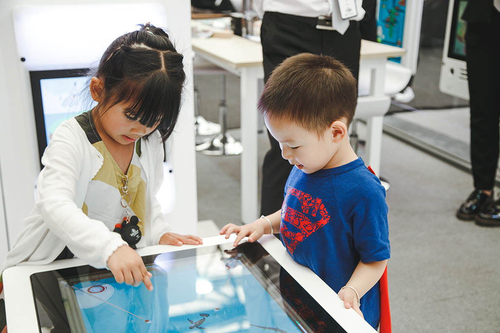 Due bambini impegnati a giocare con i sistemi di gioco interattivi di IKC Due bambini impegnati a giocare con i sistemi di gioco interattivi di IKC
