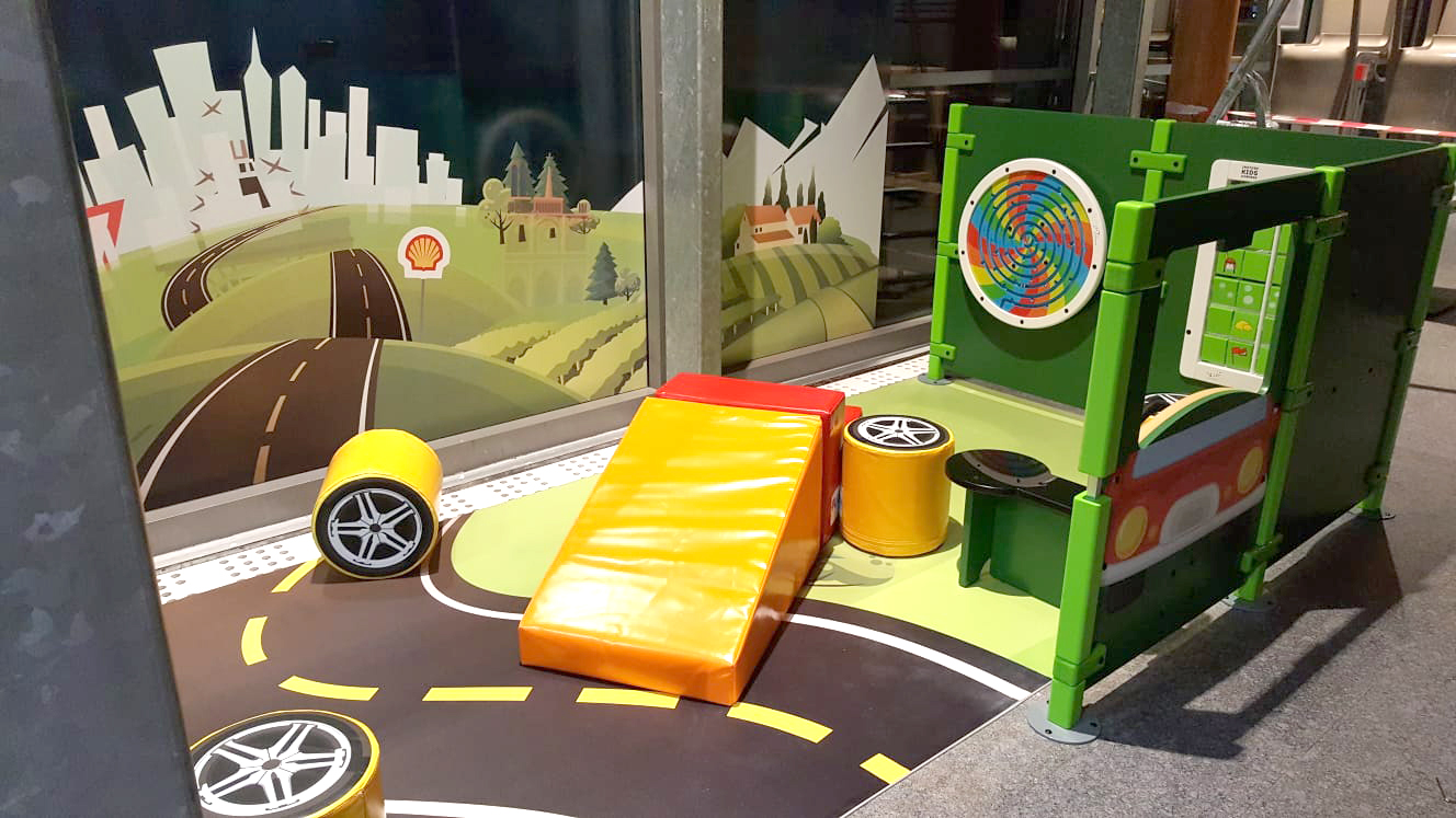 Angolo giochi per bambini alla stazione di servizio Shell in Francia con vari moduli di gioco e giochi a muro